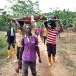 Local residents carry woman in labour on wooden door to nearby clinic